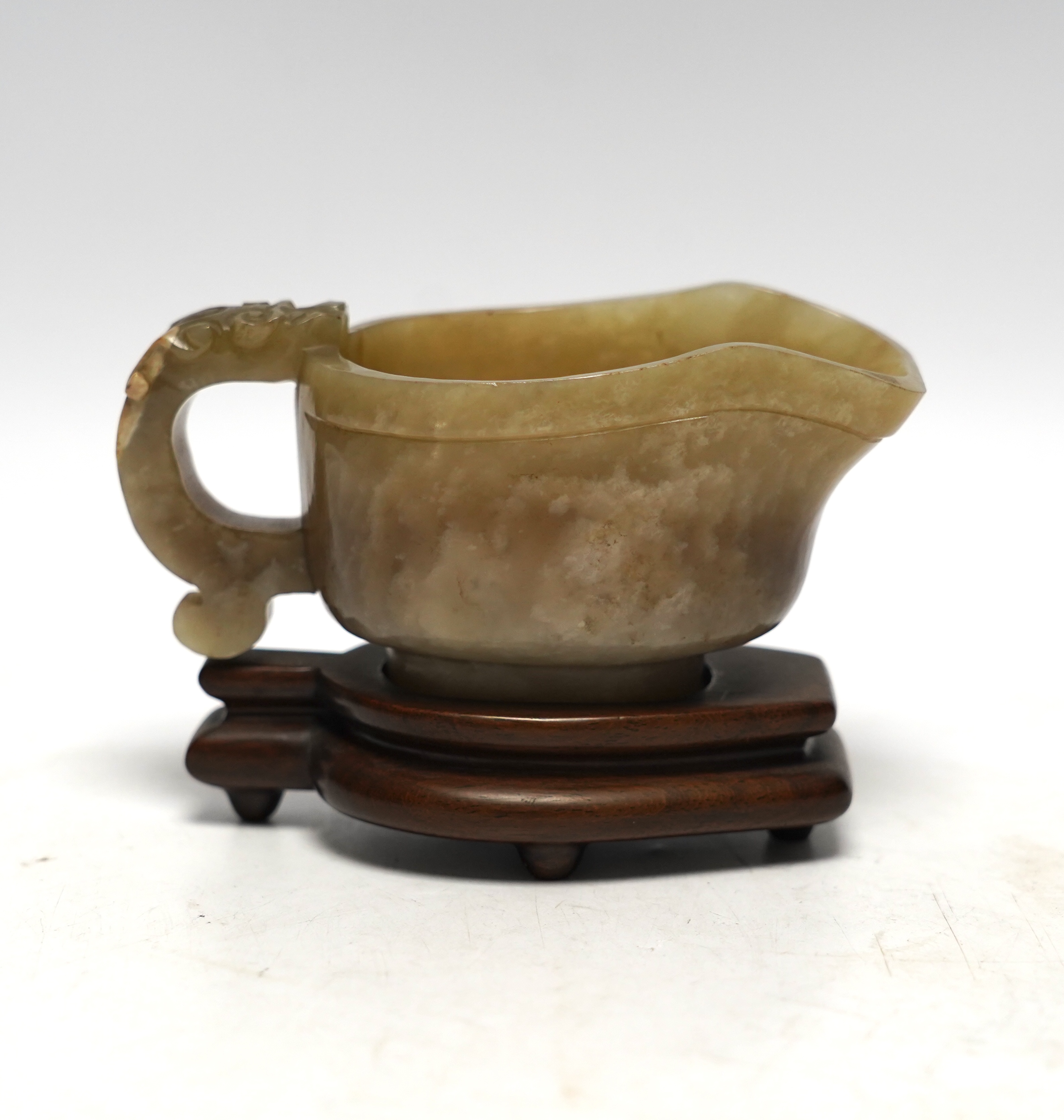 An 18th century Chinese archaistic jade pouring vessel, yi, with carved dragon handle, 6cm high, on a hardwood stand